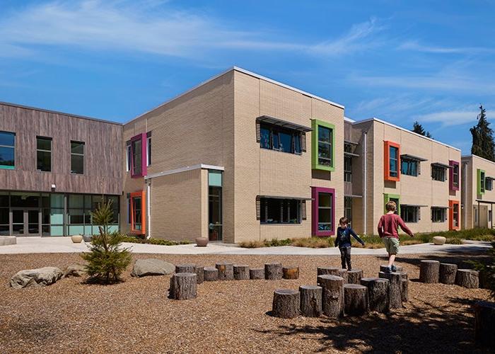 outdoor seating area with logs in front of a white brick building with colorful window frames